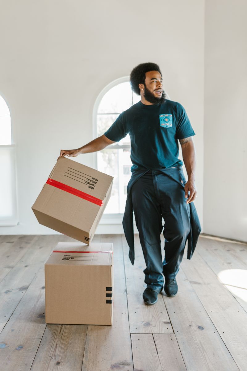 An A2B mover carefully carrying a labeled moving box into a bright, empty home